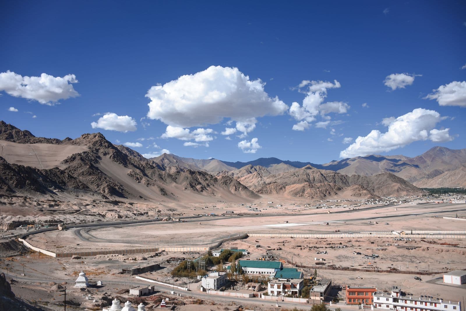 Leh town below bare mountains and a wide blue sky